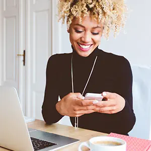 An image of someone smiling while looking at a phone